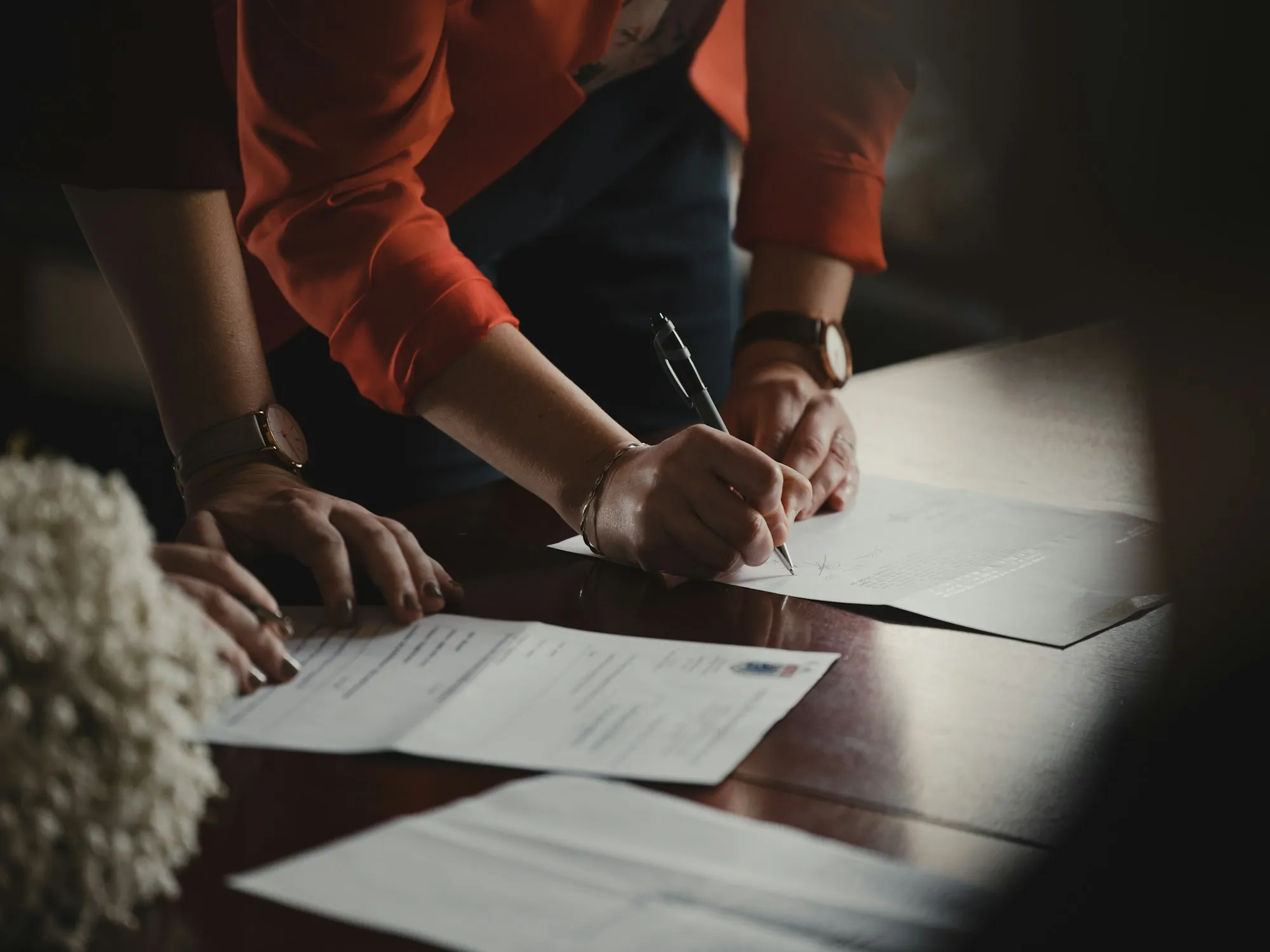 Two people signing papers at a wooden table, illustrating the California Transfer Disclosure Statement for a home sale in Maricopa
