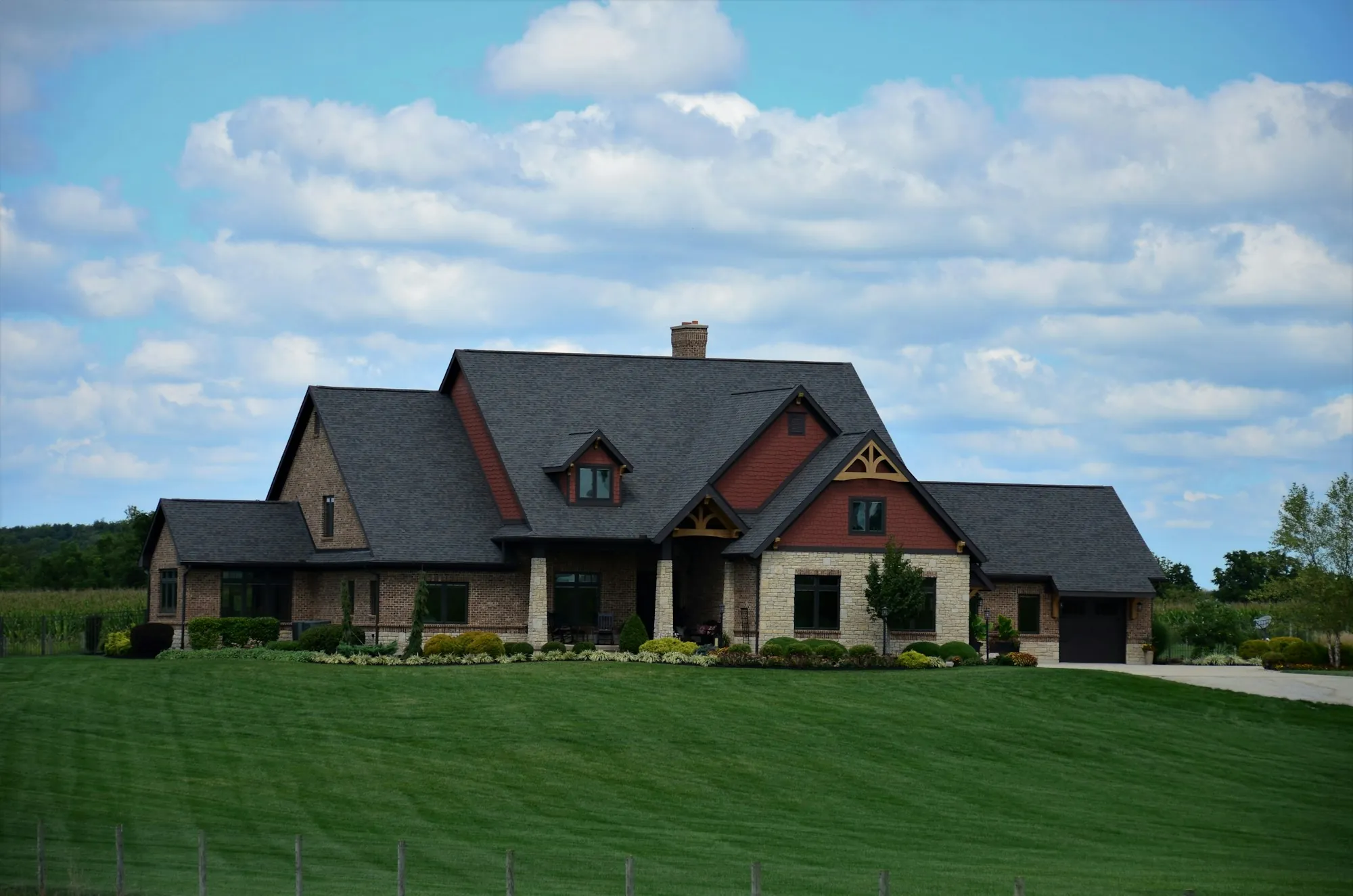 Craftsman-style house with stone accents behind a large lawn