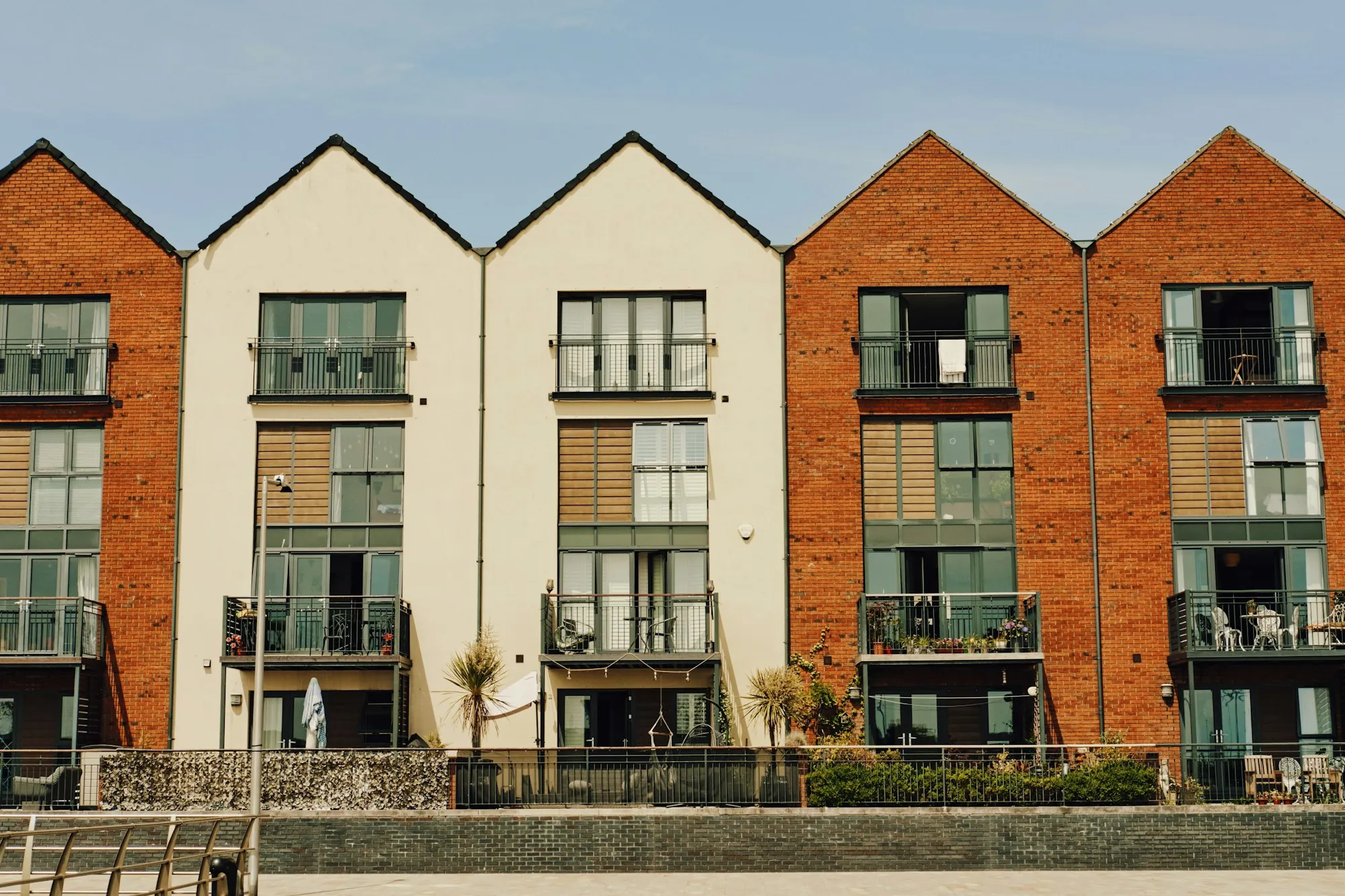 Row of modern townhouses with peaked roofs and balconies